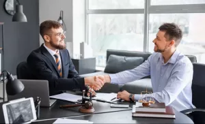 advogado e cliente dando aperto de mãos representando a importância do seguro para advogados