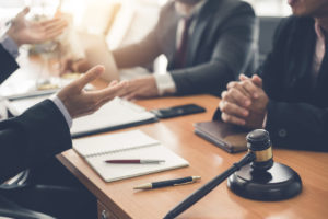 Reunião entre executivos em mesa com documentos e martelo referente ao seguro no processo de recuperação judicial.